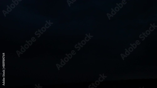 Flashes of lightning in the night sky among thunderclouds.