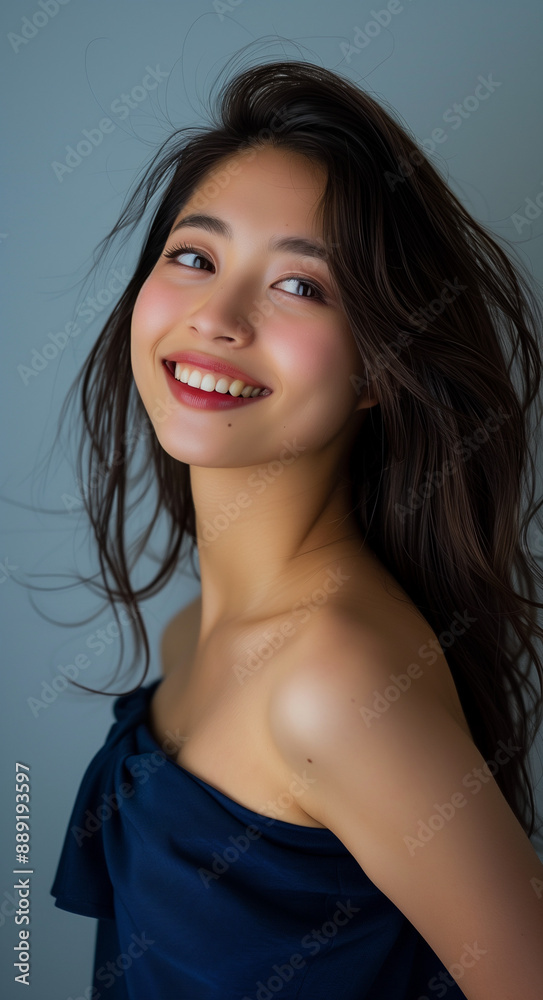 Beautiful Japanese woman with long hair wearing makeup and smiling while dressed in a blue dress with a simple background. Beautiful Japanese woman with long hair wearing makeup and smiling while dressed in a blue dress with a simple background.