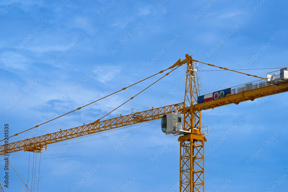 Construction tower crane are working. close up view on blue sky background. Construction tower crane are working. close up view on blue sky background.