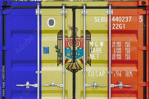 Moldova flag depicted on metal doors of shipping cargo container outdoors in docks area close up photo