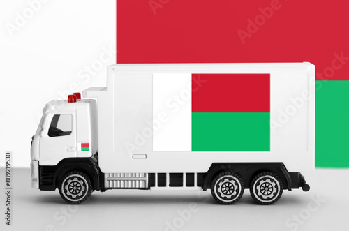 Madagascar flag depicted on side wall of white delivery van close up. Shipping and local delivery concept