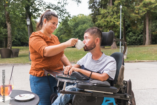 Obraz na plátne Girlfriend assisting her boyfriend with physical disability drinking coffee in a cafe