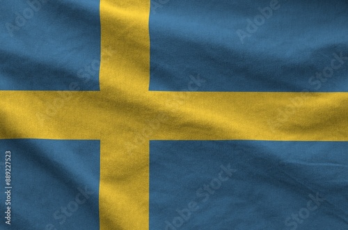 Sweden flag depicted on folded wavy fabric of old cloth close up photo