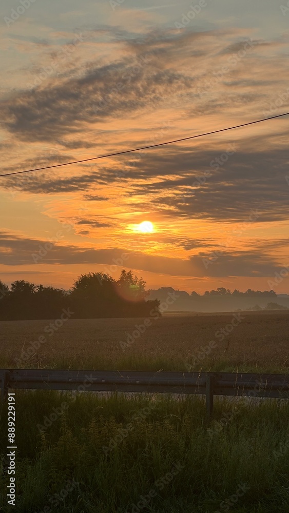 Fototapeta premium Sonnenaufgang in Orange mit Bewölkung und malerischen Farben. wunderschön