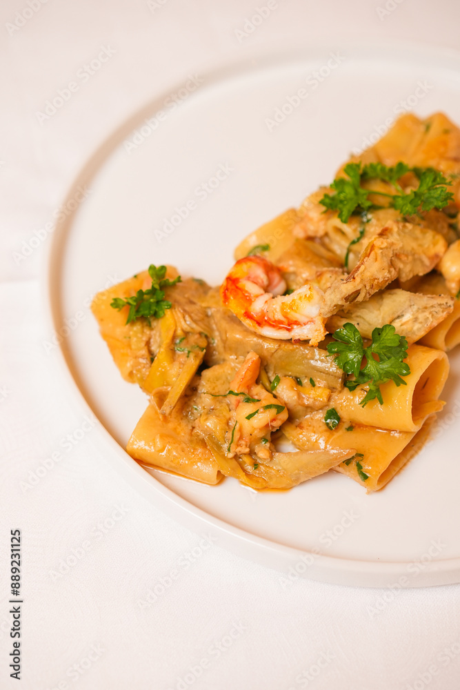 Paccheri con gamberi, carciofi e prezzemolo serviti in un ristorante come primo piatto Paccheri con gamberi, carciofi e prezzemolo serviti in un ristorante come primo piatto