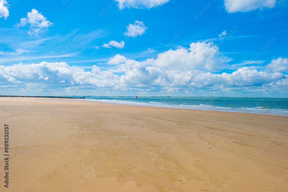Sand beach along a sea under a blue cloudy sky in bright sunlight in summer, Walcheren, Zeeland, the Netherlands, July, 2024 Sand beach along a sea under a blue cloudy sky in bright sunlight in summer, Walcheren, Zeeland, the Netherlands, July, 2024