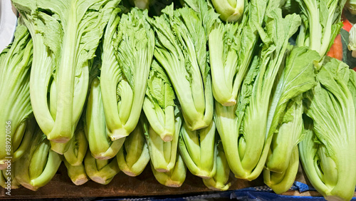 Fresh green mustard greens displayed at a market stall, showcasing their large leaves