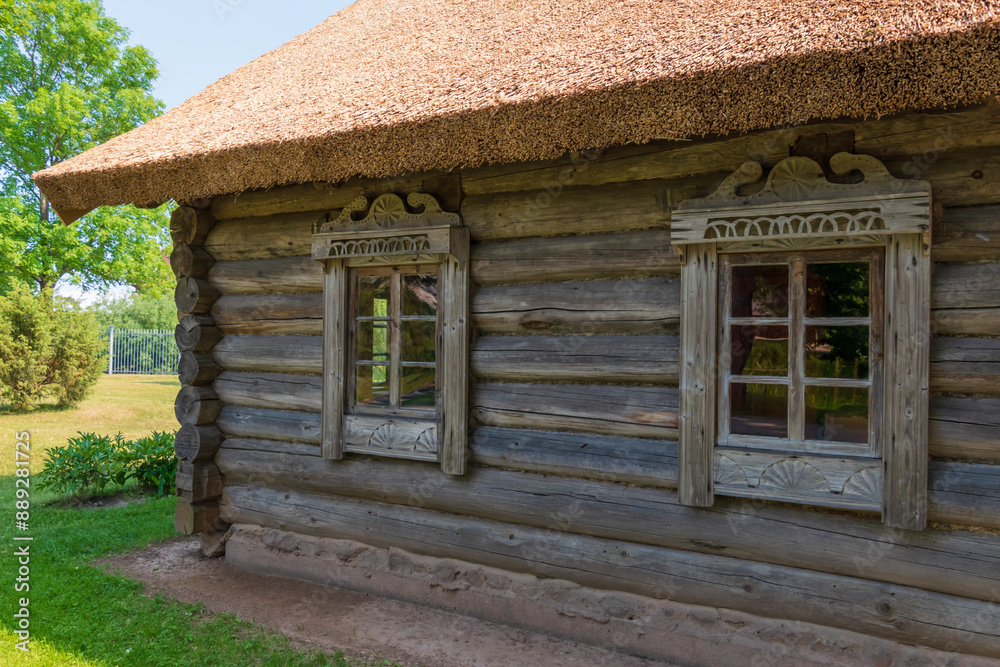 an old log house with a reed roof and decorated window frames an old log house with a reed roof and decorated window frames