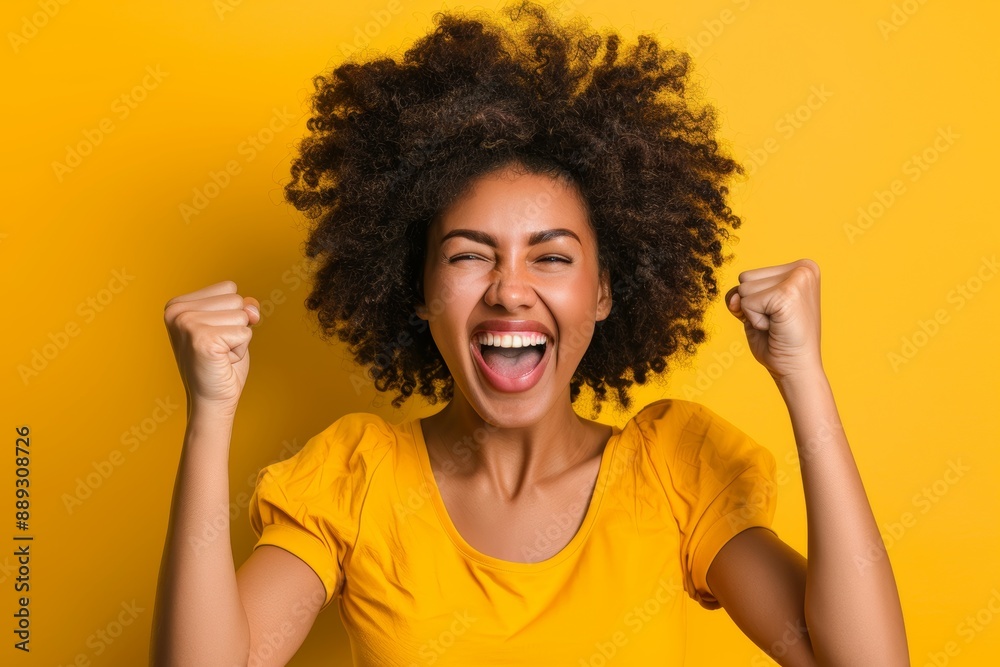 Black woman with fist celebrating promotion or lottery bonus on yellow background. Happy model, deal, or lottery winner in studio Black woman with fist celebrating promotion or lottery bonus on yellow background. Happy model, deal, or lottery winner in studio