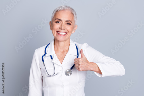 Photo of charming senior lady specialist doctor surgeon wear white robe thumb up sign isolated on grey color background