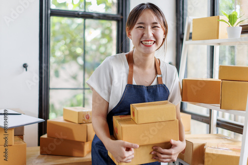 Portrait business woman smile and use laptop checking information on parcel shipping box before send to customer. Entrepreneur small business working at home. SME business online marketing.