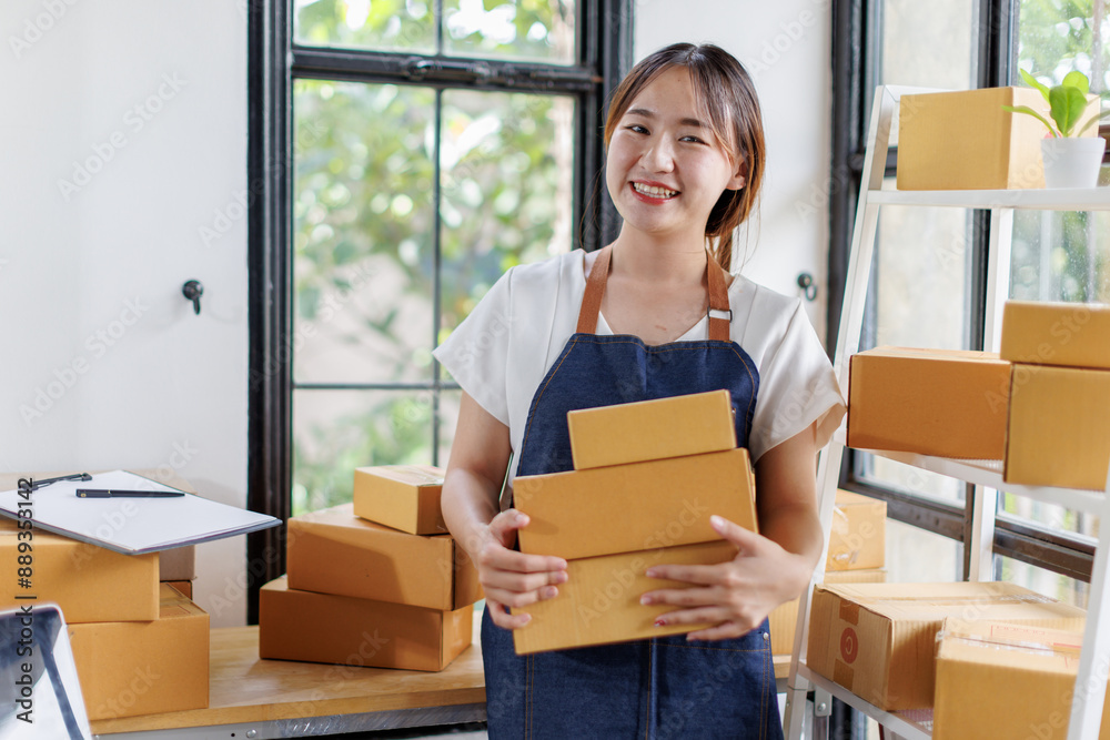 Portrait business woman smile and use laptop checking information on parcel shipping box before send to customer. Entrepreneur small business working at home. SME business online marketing. Portrait business woman smile and use laptop checking information on parcel shipping box before send to customer. Entrepreneur small business working at home. SME business online marketing.