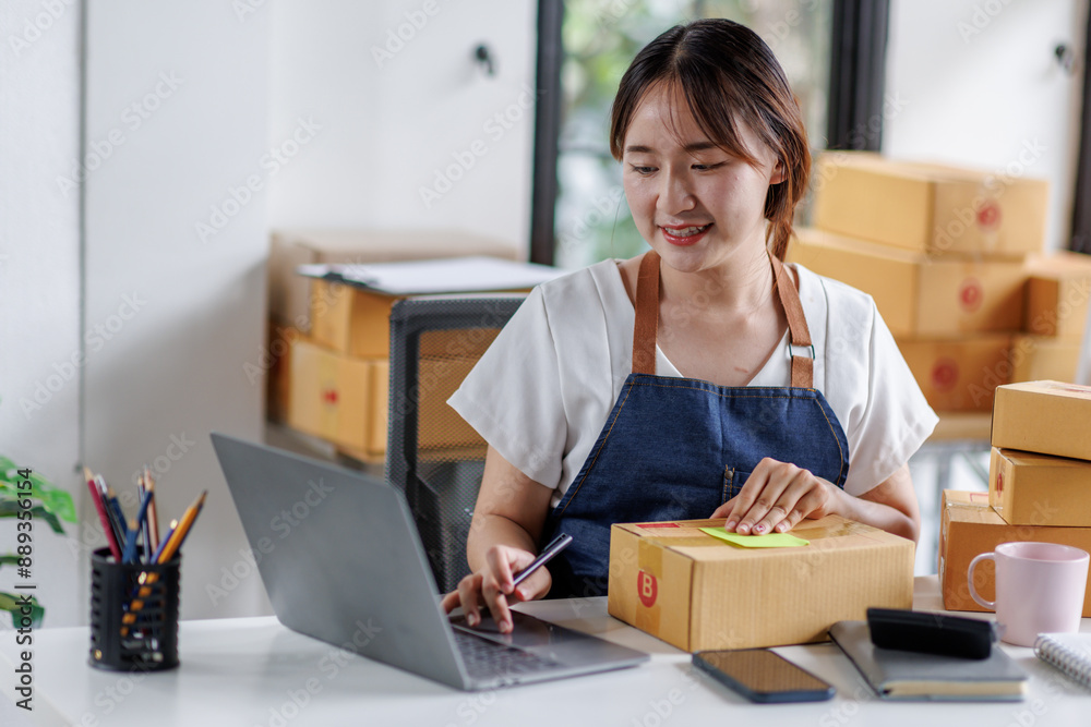 Portrait business woman smile and use laptop checking information on parcel shipping box before send to customer. Entrepreneur small business working at home. SME business online marketing. Portrait business woman smile and use laptop checking information on parcel shipping box before send to customer. Entrepreneur small business working at home. SME business online marketing.