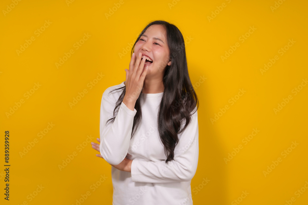 Young woman in a white shirt laughs joyfully against a yellow background, radiating happiness and confidence with her genuine smile and laughter Young woman in a white shirt laughs joyfully against a yellow background, radiating happiness and confidence with her genuine smile and laughter