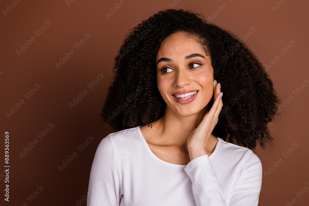 Photo of pretty young girl touch cheek look empty space wear pullover isolated on brown color background Photo of pretty young girl touch cheek look empty space wear pullover isolated on brown color background