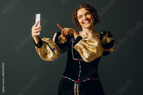 Portrait of a young aristocratic woman doing photo selfie with mobile phone and dressed in a medieval dress photo