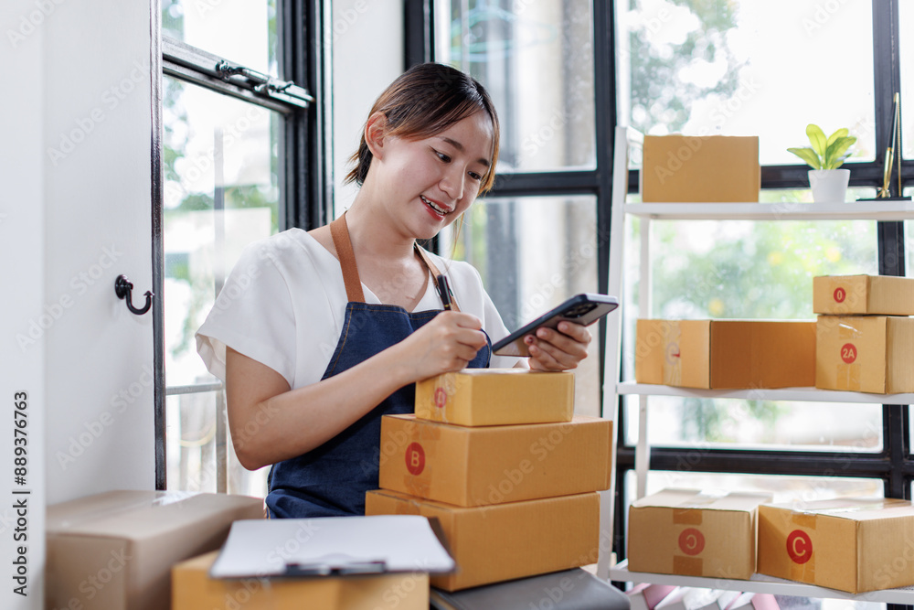 Entrepreneurs small business SME independent asian woman work at home use calculator, phone and laptop for commercial checking. online marketing packing boxes SME sellers concept, E, sme online sales Entrepreneurs small business SME independent asian woman work at home use calculator, phone and laptop for commercial checking. online marketing packing boxes SME sellers concept, E, sme online sales