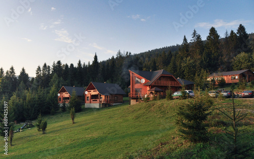 Summer cottages on a mountain slope. Wooden houses on a hill surrounded by pine tree forest.