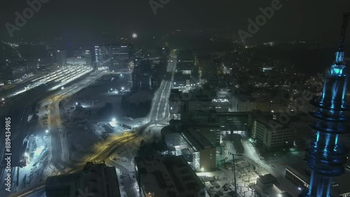 Helsinki.Finland-December 31.2021: Drone shot of the tv tower in Pasila Helsinki during nighttime. Snowfall. Lights. Amazing cityscape. Wintertime. Camera slowly moving backwards. photo