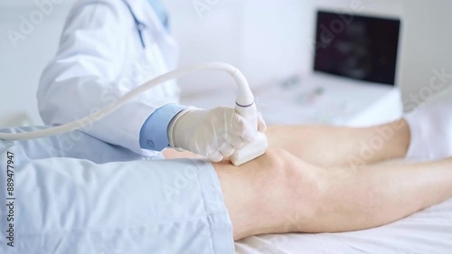 Doctor woman wearing blue medical gloves performing knee ultrasound exam on male patient. Medicine, orthopedic service concept photo