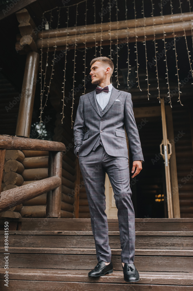 Stylish young groom, male businessman in a gray suit walks along the stairs, steps of a wooden house. Wedding photography, portrait. Stylish young groom, male businessman in a gray suit walks along the stairs, steps of a wooden house. Wedding photography, portrait.