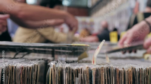 People browsing vinyl records in a music store, surrounded by retro albums in physical format