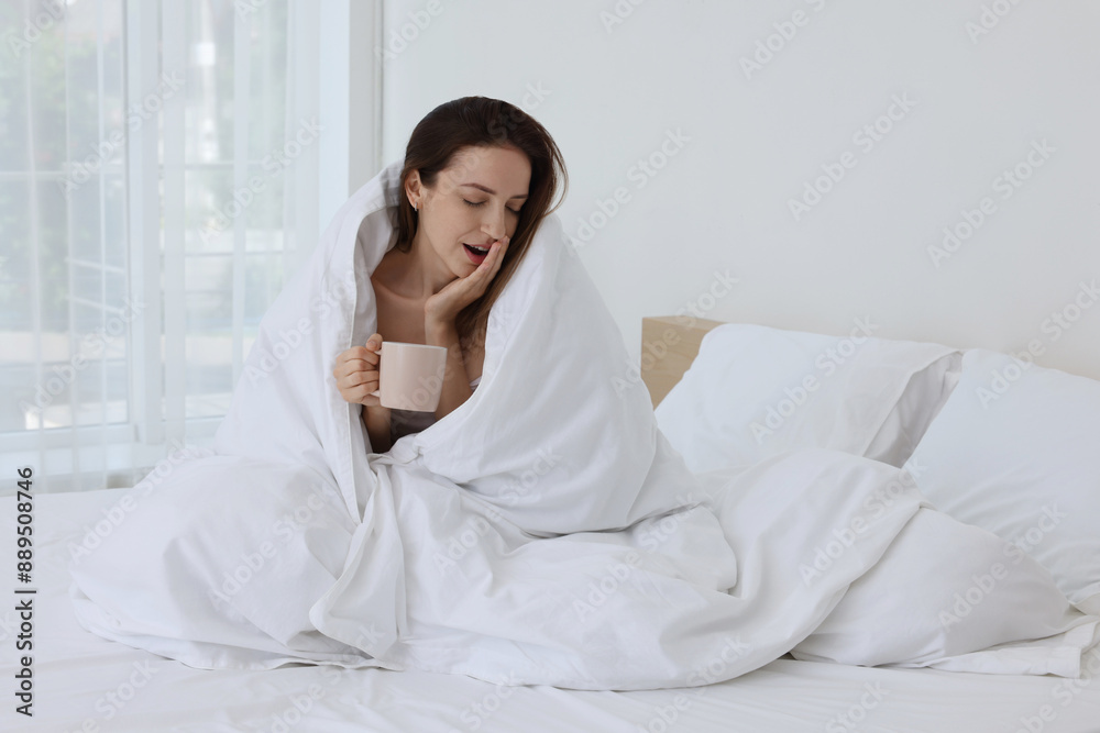 Bedtime. Woman wrapped in blanket holding cup of drink on bed indoors Bedtime. Woman wrapped in blanket holding cup of drink on bed indoors