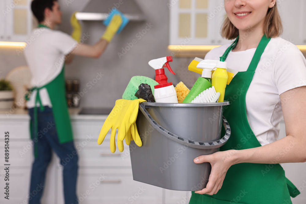 Cleaning service worker holding bucket with supplies in kitchen, closeup Cleaning service worker holding bucket with supplies in kitchen, closeup
