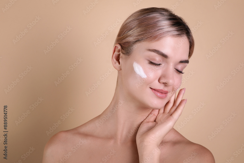 Beautiful woman with cream on her face against beige background, space for text Beautiful woman with cream on her face against beige background, space for text