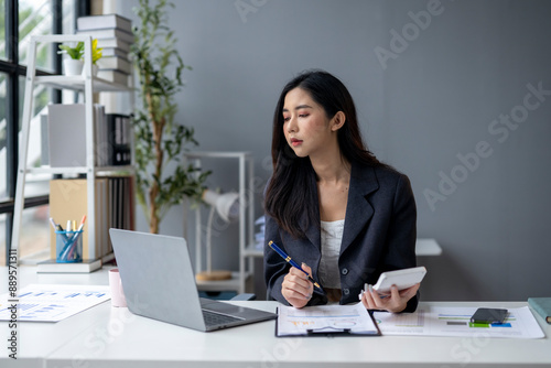 A woman is sitting at a desk with a laptop and a calculator