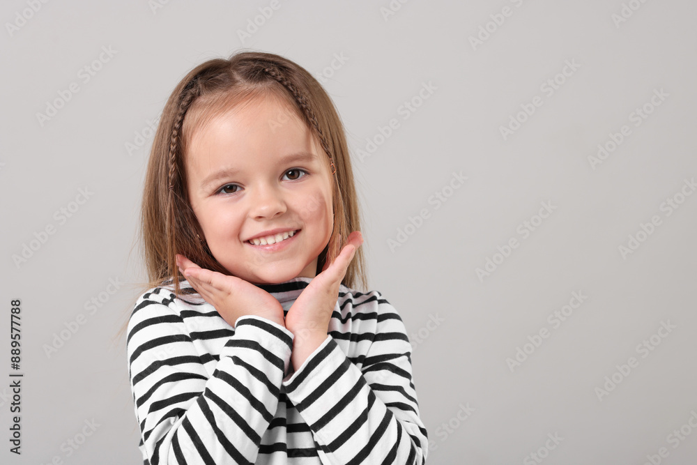 Portrait of happy little girl on grey background, space for text Portrait of happy little girl on grey background, space for text