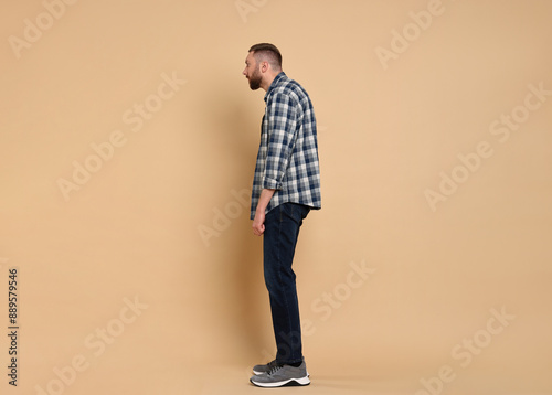 Man with poor posture on pale orange background