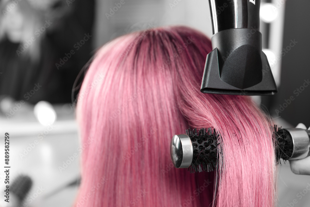 Naklejka premium Hairdresser blow drying client's pink hair in salon, closeup