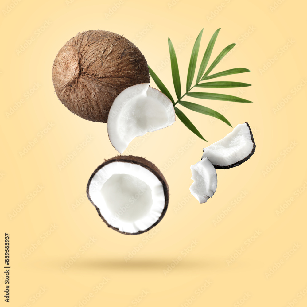Coconuts and green leaf falling on beige background Coconuts and green leaf falling on beige background