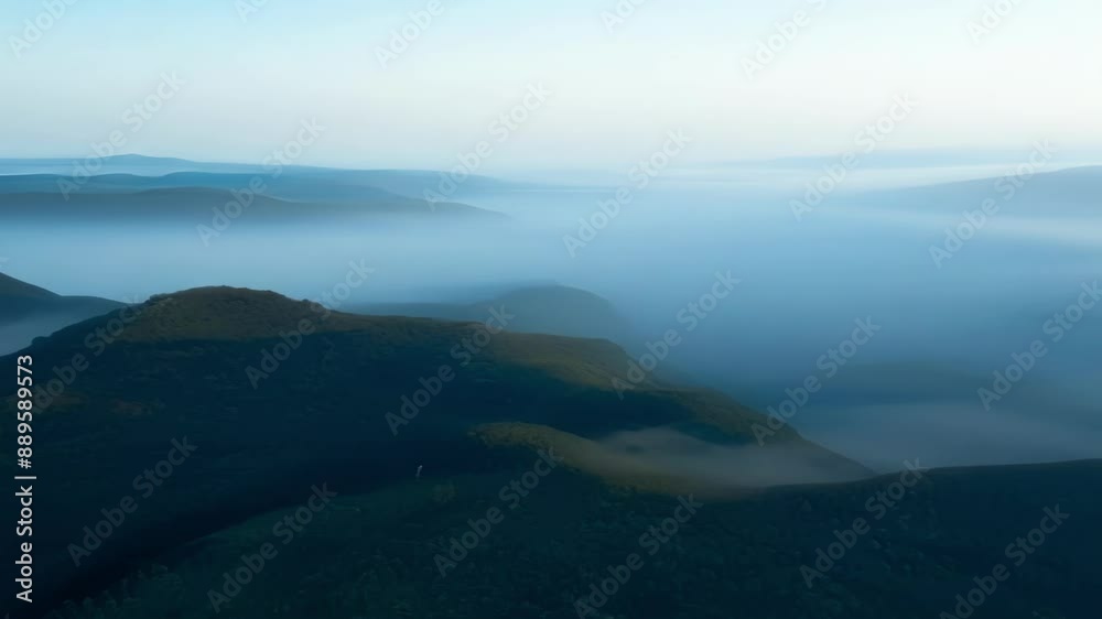 As we soar above the misty hills the faint outline of mountaintops can be seen in the distance.