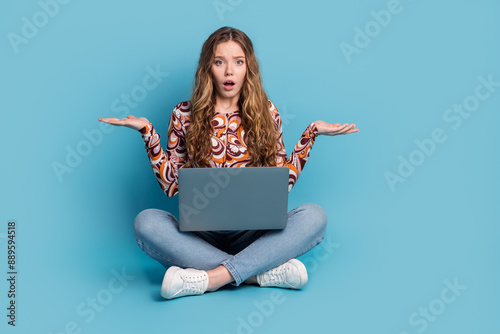 Full length portrait of nice young girl laptop shrug shoulders wear top isolated on blue color background photo