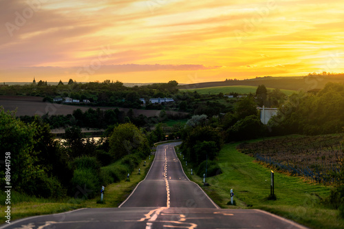 Gerade Straße in hügeliger Landschaft bei Sonnenuntergang photo