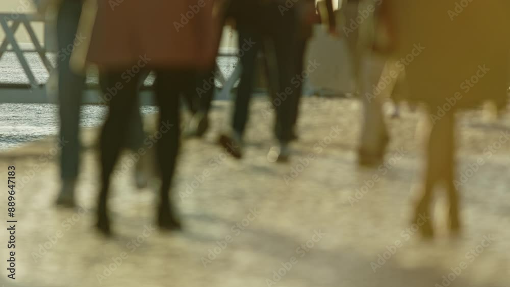 A group of people walking on a sidewalk A group of people walking on a sidewalk