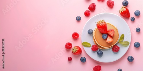 Pancake stack with berries on pink background. Delicious breakfast concept featuring fresh strawberries, raspberries, blueberries, and mint leaves. For food blogs, marketing, and culinary websites