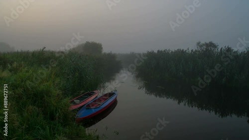 Dawn on the river with kayaks standing near the shore.