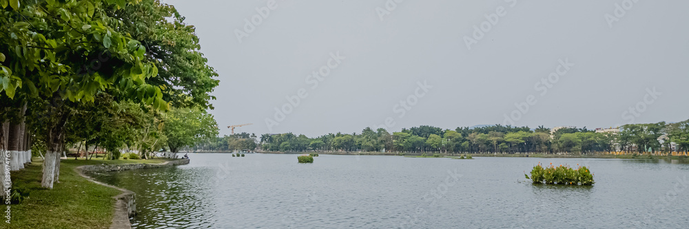 Serene view of a tranquil park lake with lush green trees, ideal for nature relaxation and environmental awareness Serene view of a tranquil park lake with lush green trees, ideal for nature relaxation and environmental awareness