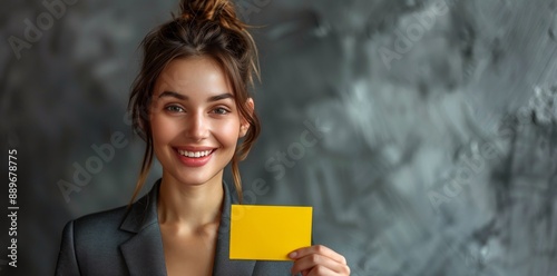 Smiling Woman Holding Yellow Card in Front of Grey Background