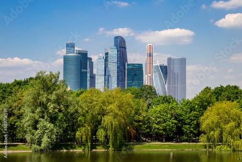 Photography View of high-rise buildings with green trees and a pond on a clear sunny day