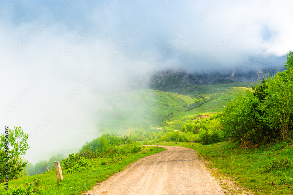 A mountain road high in the mountains among low clouds. The North Caucasus. Russia A mountain road high in the mountains among low clouds. The North Caucasus. Russia