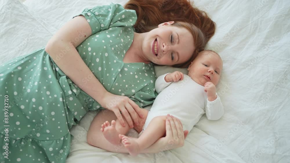 Happy family at home. Mother playing with little toddler child on bed. Mom baby relax playing having fun together. Mother looks at camera with love care. Mom of breast feeding baby rest in living room Happy family at home. Mother playing with little toddler child on bed. Mom baby relax playing having fun together. Mother looks at camera with love care. Mom of breast feeding baby rest in living room