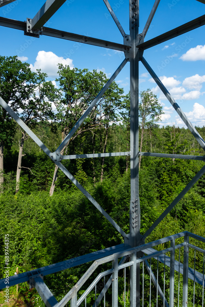 Bolted connections of steel elements of the observation tower. Construction details of galvanized steel against a green trees background