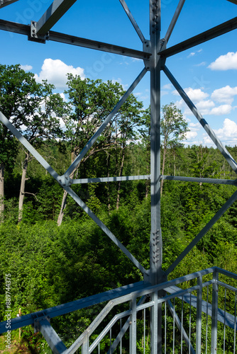 Obraz na płótnie Bolted connections of steel elements of the observation tower. Construction details of galvanized steel against a green trees background w salonie