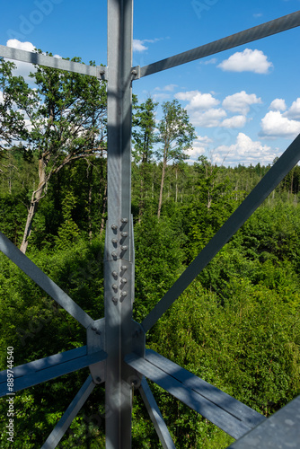 Bolted connections of steel elements of the observation tower. Construction details of galvanized steel against a green trees background