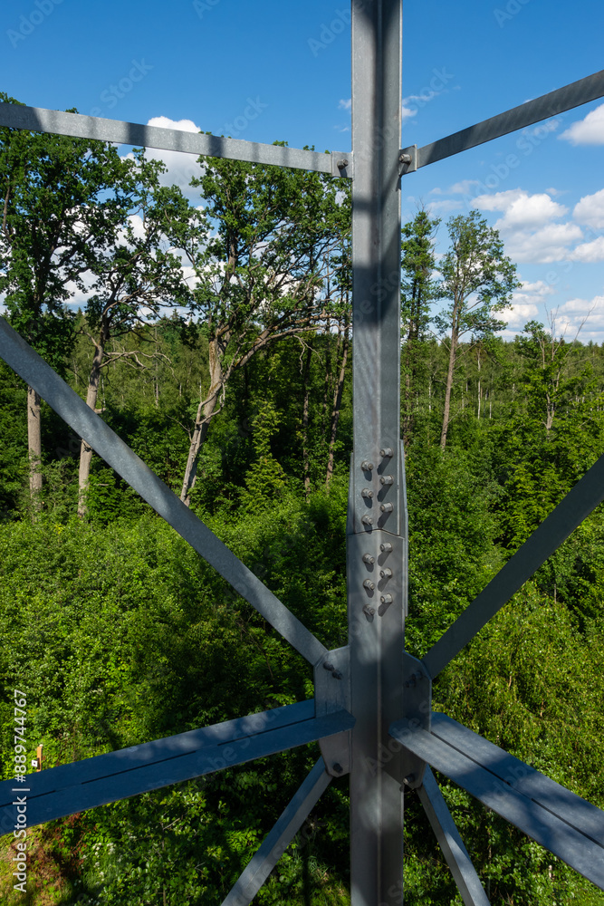 Bolted connections of steel elements of the observation tower. Construction details of galvanized steel against a green trees background