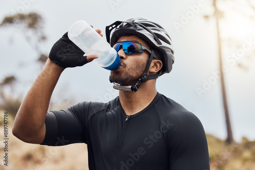 Man, break and drinking water with bottle while cycling for fitness, health and french sports competition. Cyclist, tired and hydration with clear liquid as athlete for race, performance and wellness photo